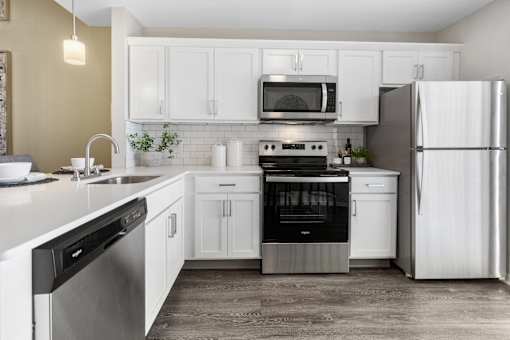 A modern kitchen with white cabinets and stainless steel appliances.