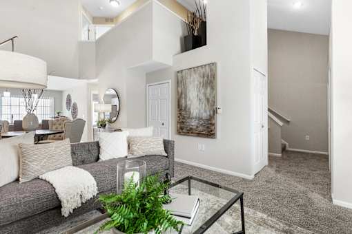 A living room with a grey couch and a large painting on the wall.