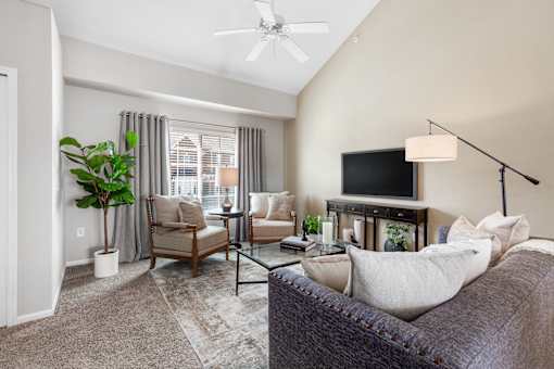 A living room with a couch, chairs, and a television.