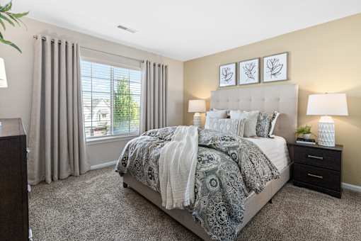 A bedroom with a large bed and a window with curtains.