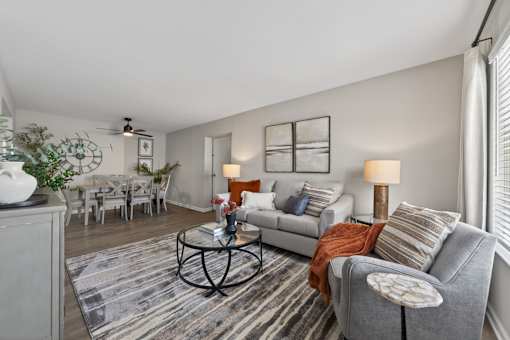A living room with a grey couch, a coffee table, and a dining table.