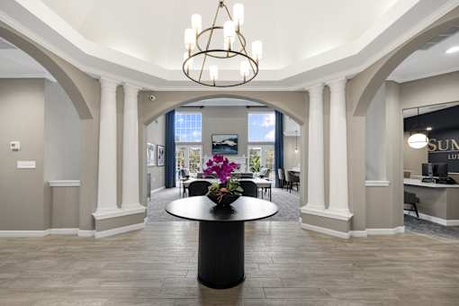 A large, elegant room with a chandelier, a table with flowers, and a reception desk.
