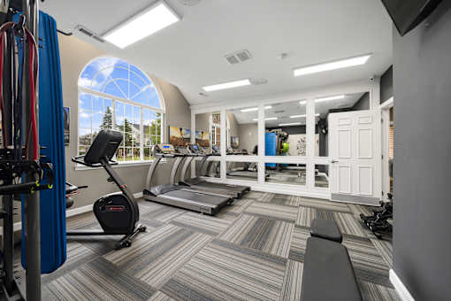 A gym with a treadmill, exercise bike, and other equipment.