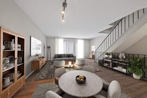 A modern living room with a grey sofa, a round table, and a wooden cabinet.