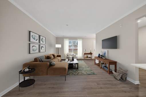 A living room with a brown couch and a television on the wall.
