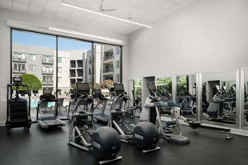 A gym with a view of apartment buildings outside the large windows.