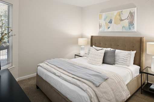 A bed with a white comforter and pillows is in the center of the image.