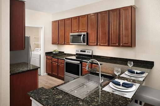 A kitchen with brown cabinets and a granite countertop.