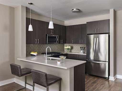 A modern kitchen with a white countertop and stainless steel appliances.