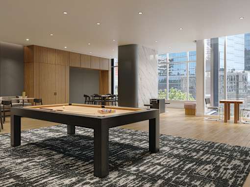 A shiny wooden pool table in a room with a black and white rug.