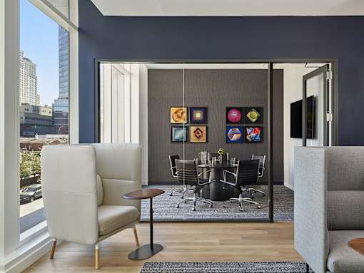 A modern living room with a grey sofa, a black table and a large window.