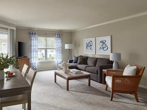 A living room with a grey couch, a wooden table and a television.