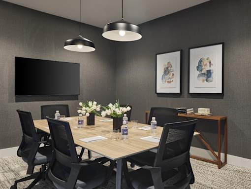 A conference room with a table, chairs, and a television.