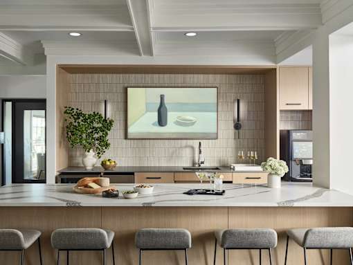 A modern kitchen with a large island and grey bar stools.