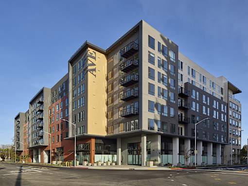 A large, modern apartment building with multiple balconies and a variety of window designs.