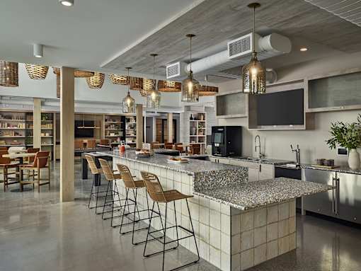 A modern kitchen with a long bar and stools.