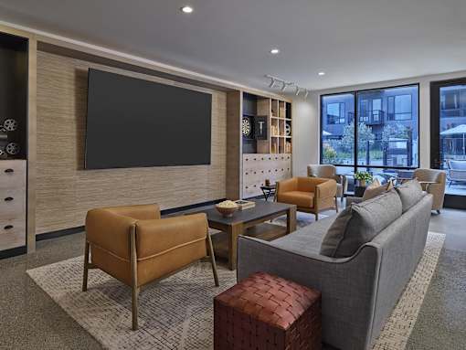 A modern living room with a grey couch, a brown chair, and a black television.
