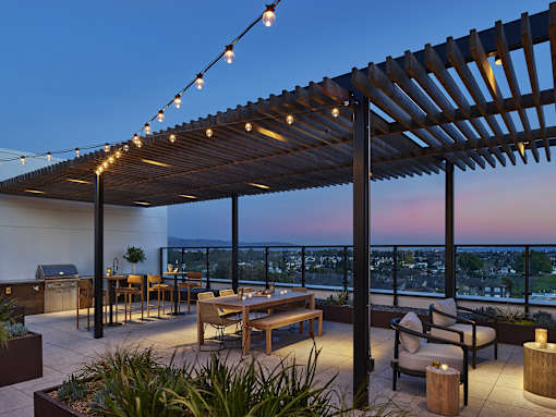 A patio with a table and chairs under a pergola with string lights.