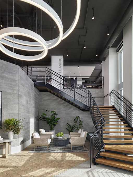 A modern interior with a staircase and a sign that says "Leasing".
