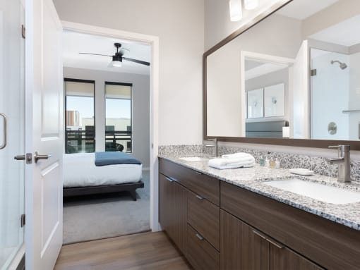 a bathroom with a sink and a mirror and a bedroom with a bed
