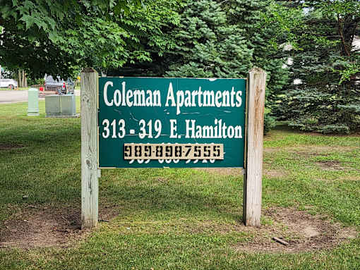 A sign for Coleman Apartments with a phone number on it.