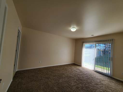 A room with a carpeted floor and a sliding glass door leading outside.