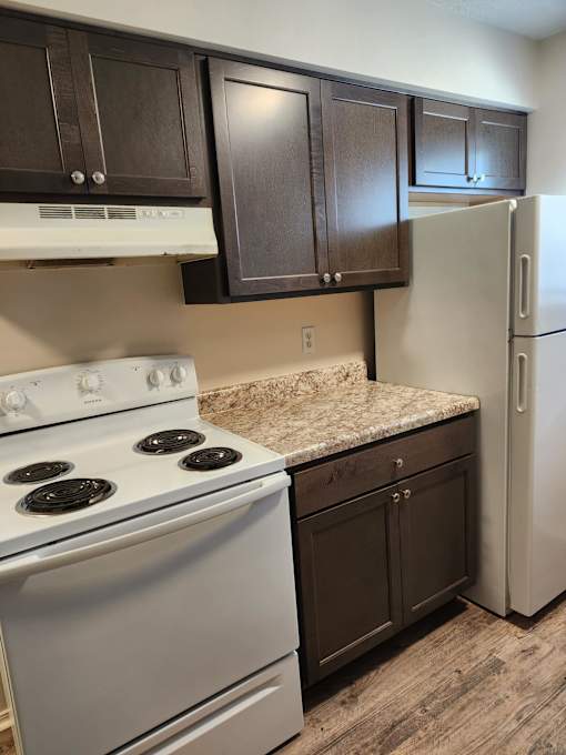 A kitchen with a white stove and a white refrigerator.