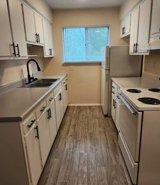 A kitchen with white cabinets and a stove top oven.