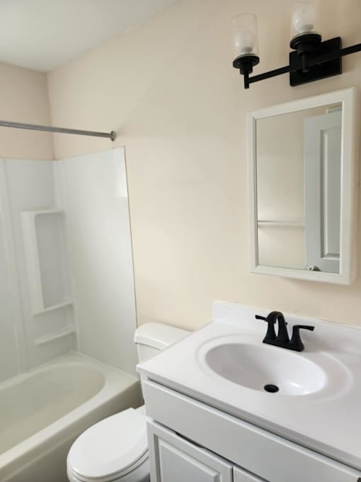 A white toilet sits next to a white sink in a bathroom.