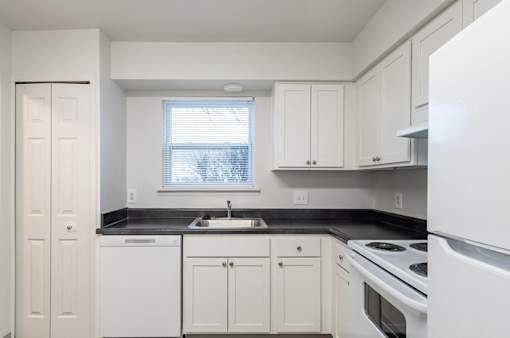 A kitchen with white cabinets and appliances.