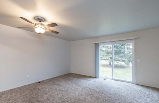 A room with a ceiling fan and carpeted floor.