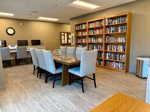 A room with a table, chairs, and a bookshelf filled with books.