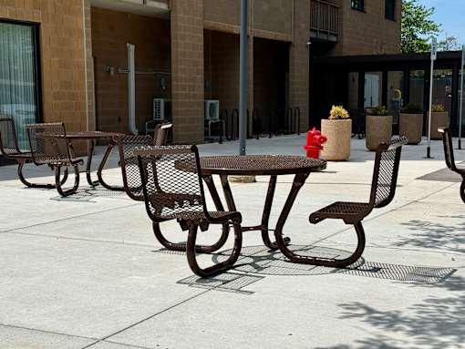 A fire hydrant is in the middle of a patio table and chairs.