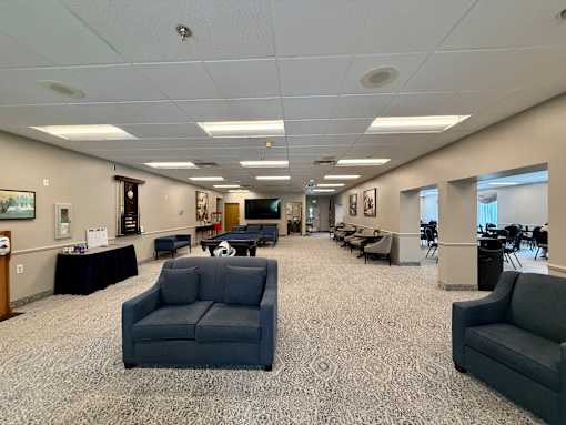 A spacious waiting room with grey couches and a patterned carpet.