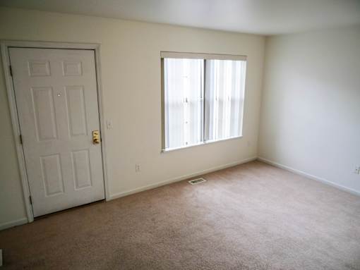 A room with a white door and a window with white curtains.