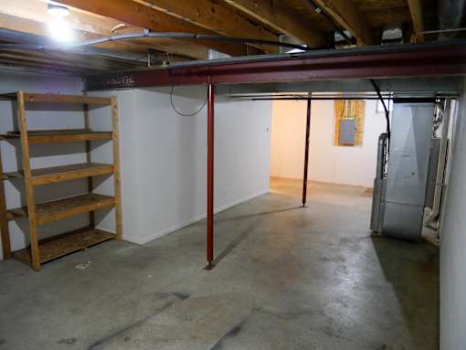 A room with a white wall and a wooden shelf.