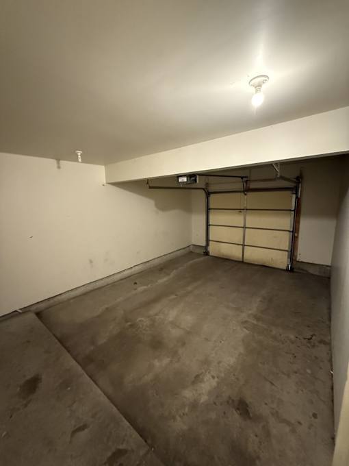 A white wall with a light on and a door in the middle.