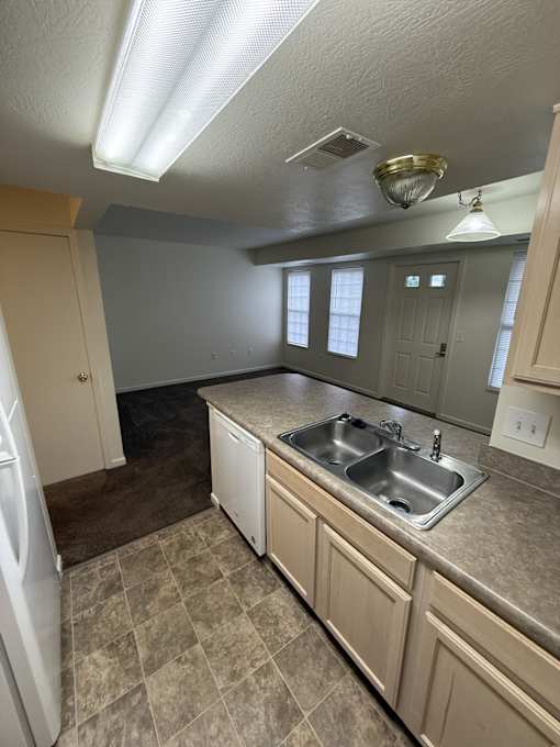 A kitchen with a sink, refrigerator, and cabinets.
