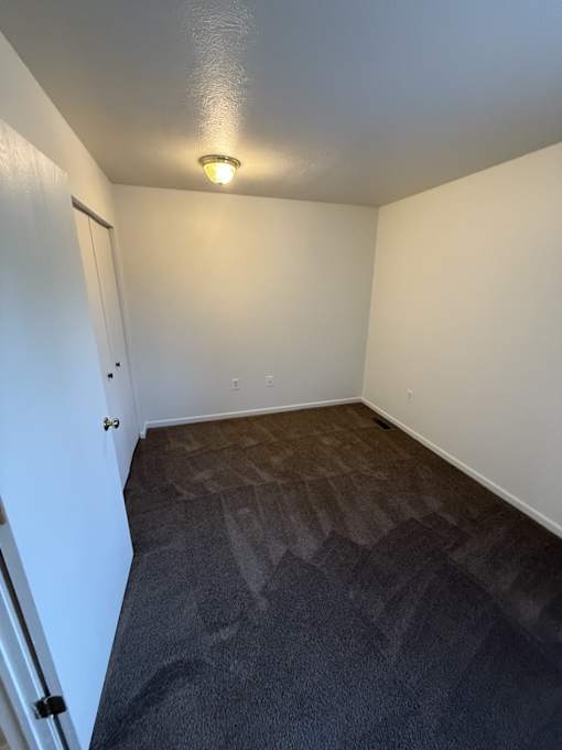 A room with a carpeted floor and a door on the left side.