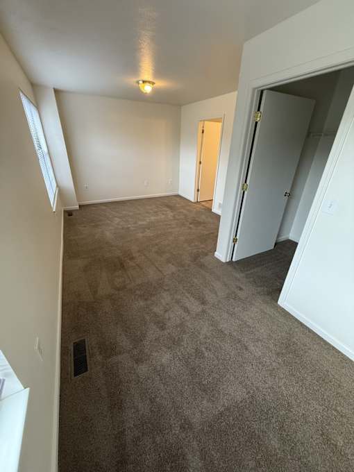 A room with a carpeted floor and a doorway leading to another room.