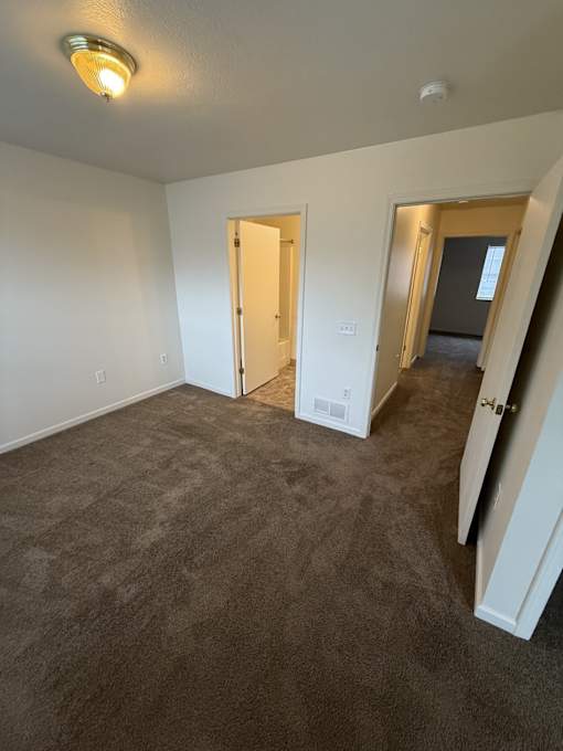 A room with carpeted floor and two open doors.