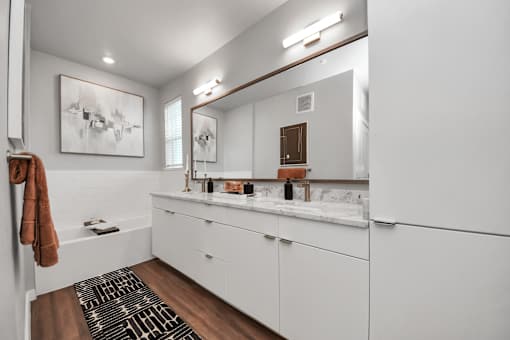 A bathroom with white cabinets and a brown rug.
