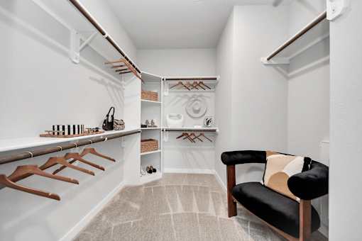 A room with a chair and a rack of clothes.