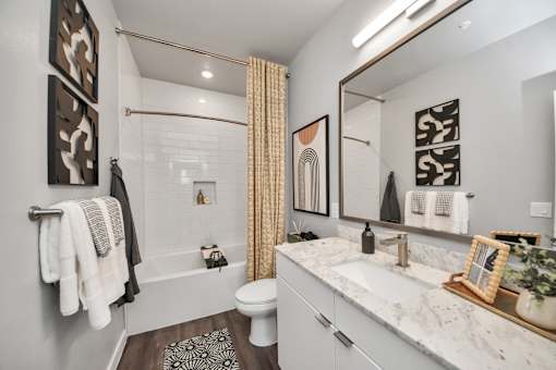 A bathroom with a white toilet, a sink, a bathtub, and a mirror.