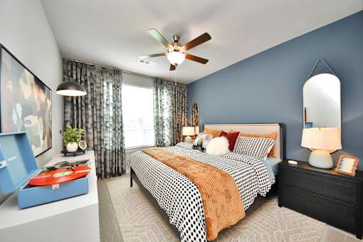 A bedroom with a bed, nightstand, and a ceiling fan.