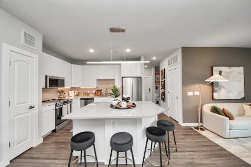 A modern kitchen with a white island and bar stools.