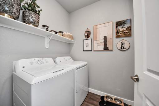 A laundry room with a washer and dryer and pictures on the wall.