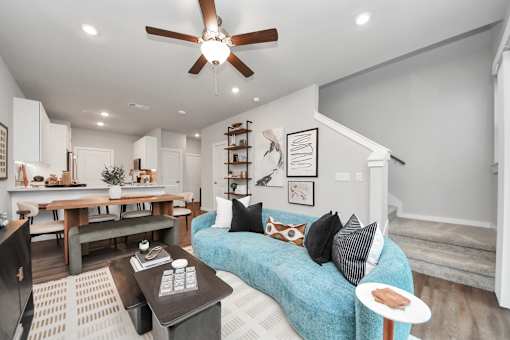 A living room with a blue couch and a ceiling fan.