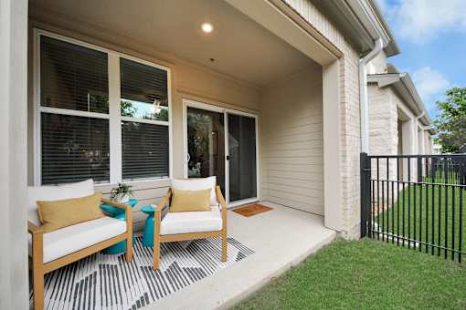A white patio with chairs and a table.