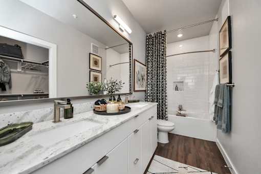 A bathroom with a marble countertop and white cabinets.